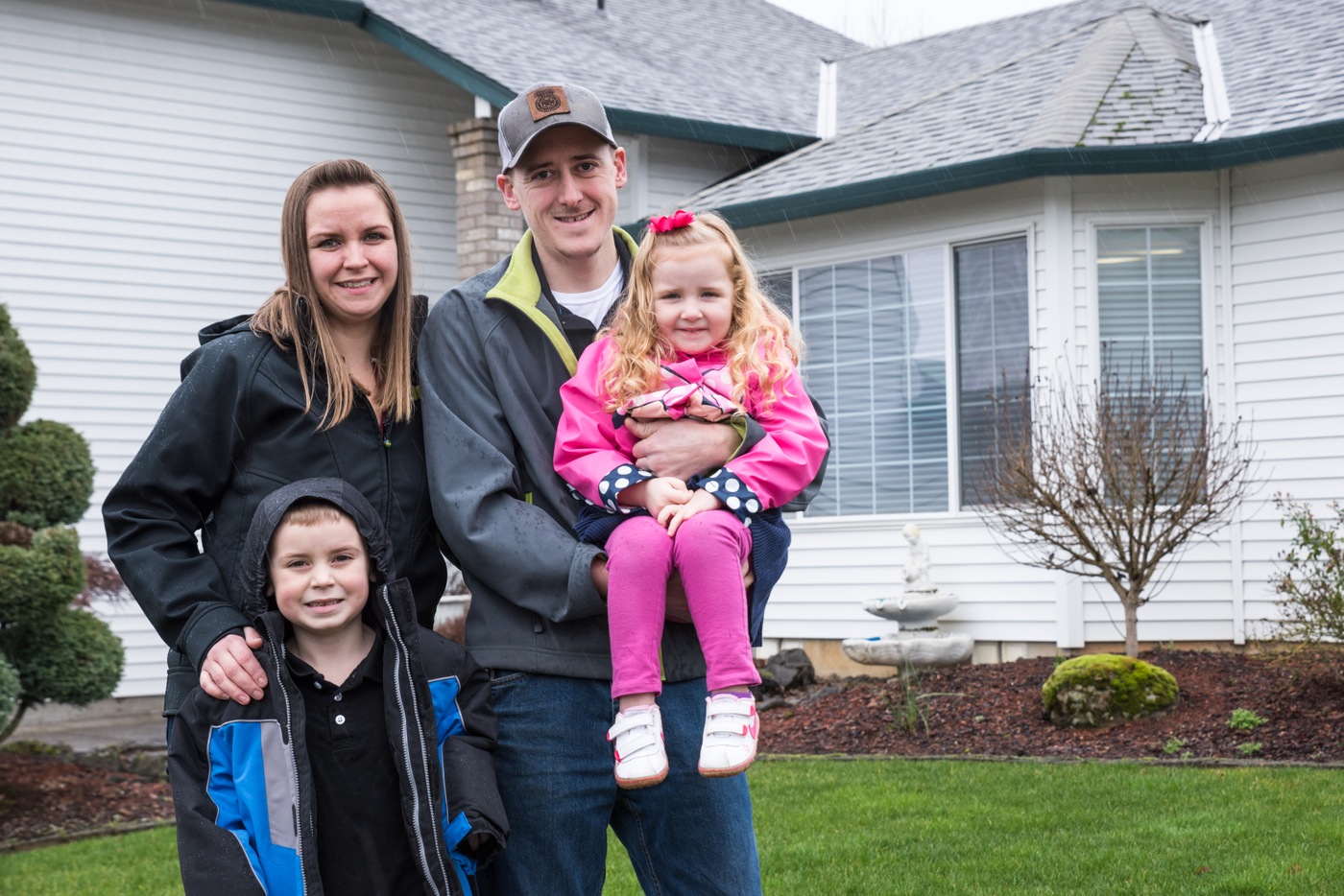 Aaron Cole and his family stand in front of the Oregon home that was nearly taken from them by online fraudsters and money mules. Photo credit: Melissa Toledo for WFG.