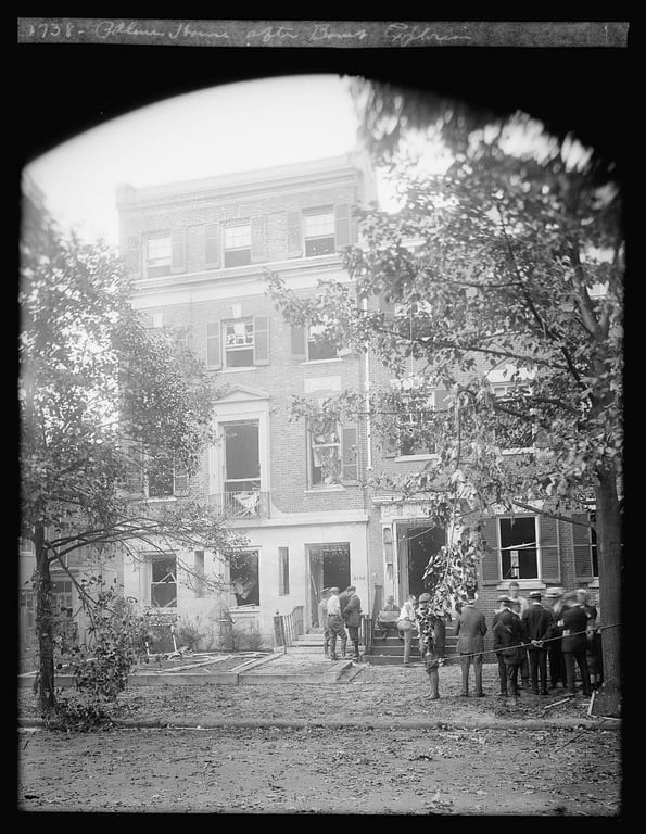 Black and white photo depicting damage to Attorney General A. Mitchell Palmer's home in Washington, D.C., with investigators and responders working outside following a June 1919 bombing. (Library of Congress photo)
