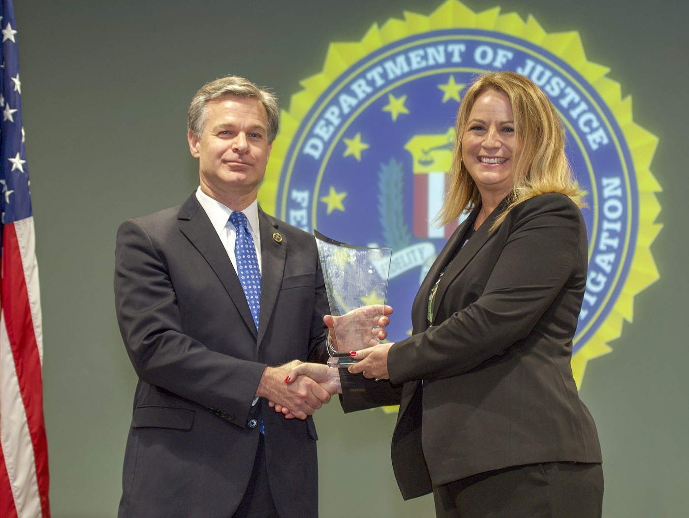 FBI Director Christopher Wray presents Anchorage Division recipient Priceless Alaska (represented by Gwen Adams) with the Director’s Community Leadership Award (DCLA) at a ceremony at FBI Headquarters on May 3, 2019.