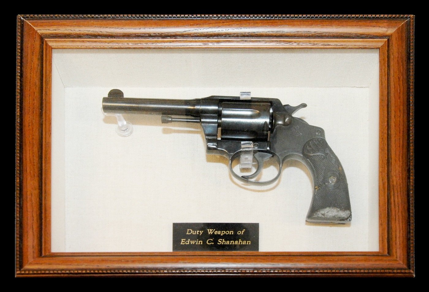 Photo of a gun in a frame. The gun belonged to Special Agent Edwin C. Shanahan, who was killed in the line of duty in 1925.