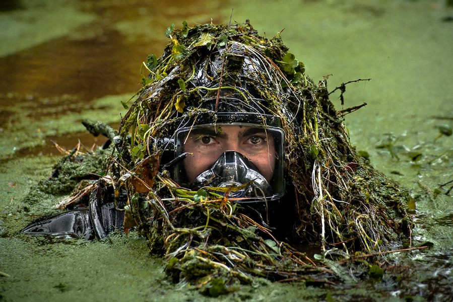 An FBI diver emerges from the murky depths of a retention pond during a search for submerged evidence.