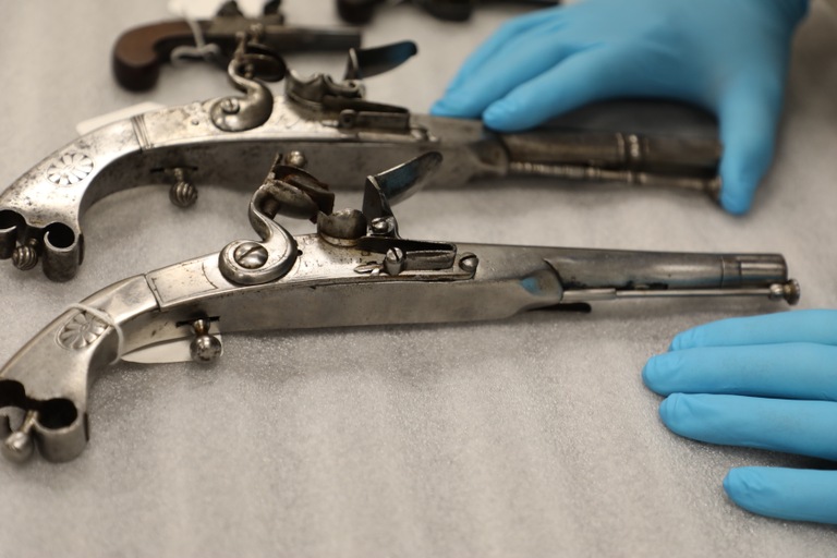 A Museum of the American Revolution employee handles two firearms recovered during an art crime investigation conducted by FBI Philadelphia and our local law enforcement partners, with help from the museum and the U.S. Attorney's Office for the Eastern District of Pennsylvania. Members of the Royal Highland Regiment, part of the British Army sent to suppress the American rebellion, carried these steel pistols.