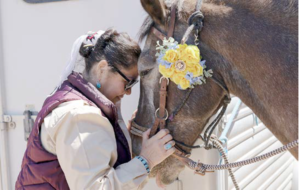 An FBI employee connects with a horse prior to saddling up for the parade at Gathering of Nations in April 2023 in Albuquerque, New Mexico.
