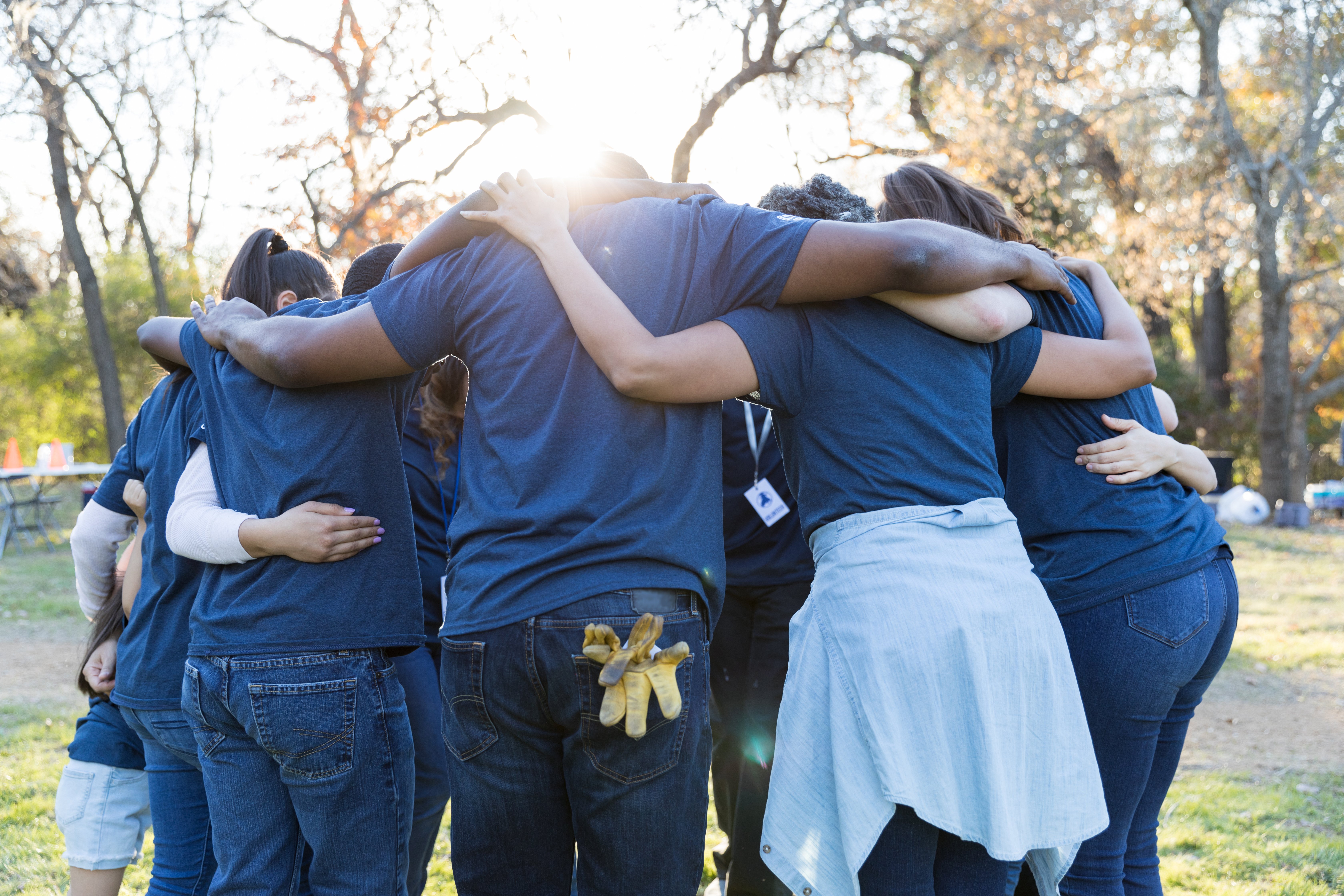 Huddle of people in blue shirts - Getty Image