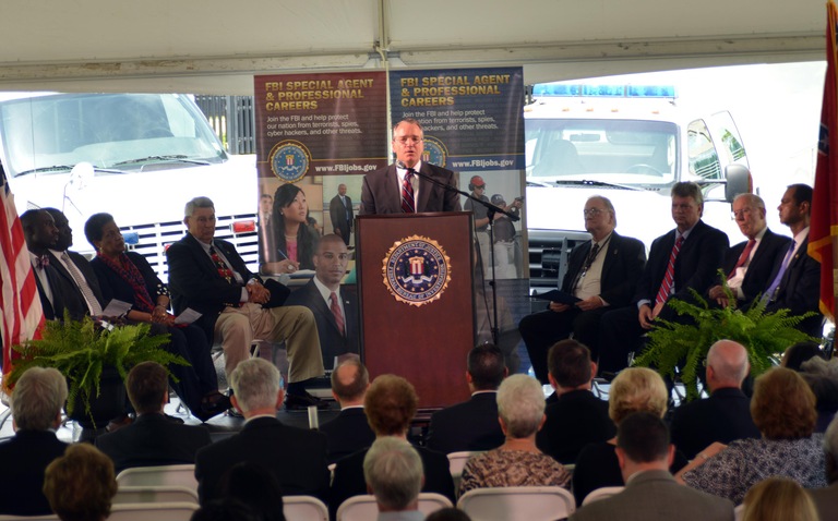 FBI Deputy Director Mark Giuliano speaks at the Jackson 50th anniversary ceremony. Seated on stage (from left) are Tony Yarber, mayor of Jackson; Reverend James Young, mayor of Philadelphia, Mississippi; Myrlie Evers-Williams, widow of slain civil rights activist Medgar Evers; Dr. David Ard, FBI chaplain; Dr. Sid Bondurant, legislative liaison and policy adviser to Mississippi Governor Phil Bryant; Mississippi Attorney General Jim Hood; former Mississippi Governor William F. Winter; and FBI Jackson Division retired Special Agent in Charge Daniel McMullen. 