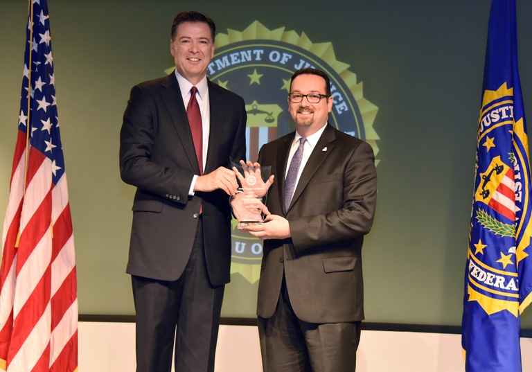 FBI Director James Comey presents Norfolk Division recipient Jonathan Zur with the Director’s Community Leadership Award (DCLA) at a ceremony at FBI Headquarters on April 28, 2017.