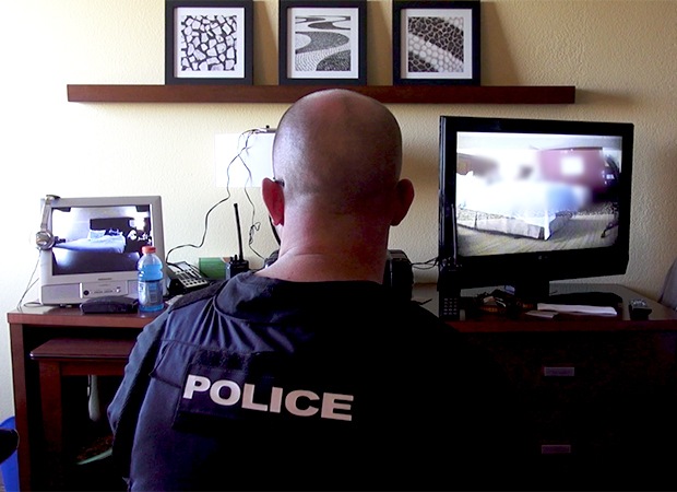 An officer with the Alexandria (Virginia) Police Department monitors an undercover sting operation in a hotel room during Operation Cross Country.