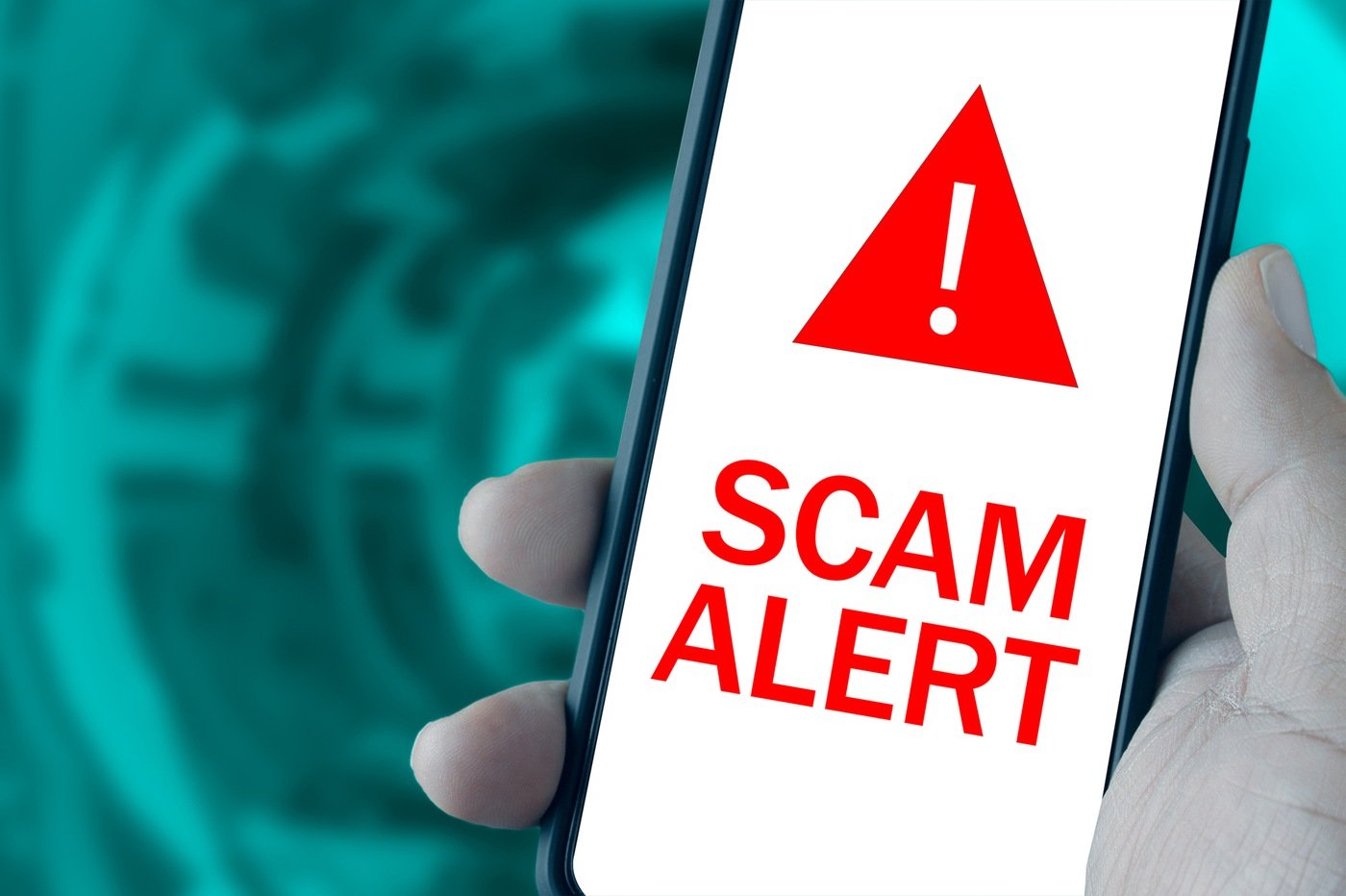 Photo of hand holding a mobile phone with a "Scam Alert" warning