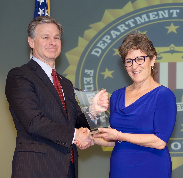 FBI Director Christopher Wray presents Pittsburgh Division recipient The Ziegenfelder Company (represented by Lisa Allen) with the Director’s Community Leadership Award (DCLA) at a ceremony at FBI Headquarters on April 20, 2018.