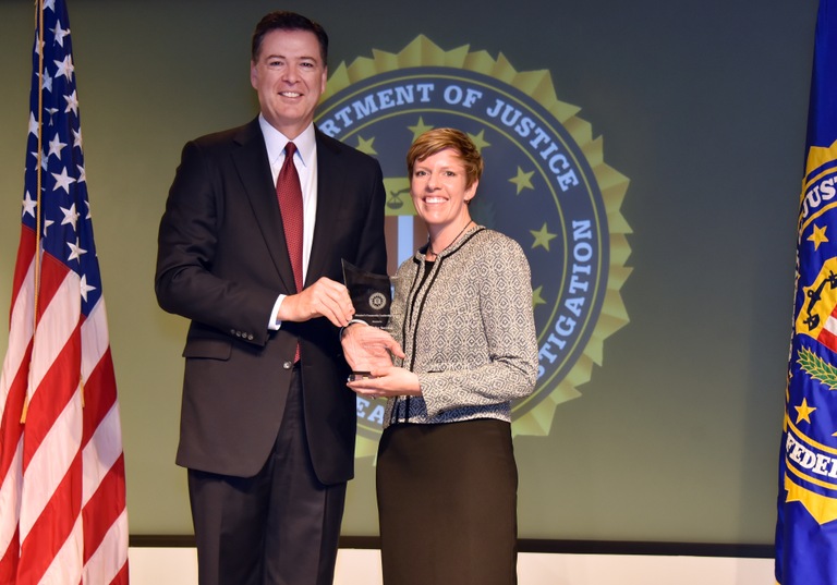 FBI Director James Comey presents Salt Lake City Division recipient South Valley Services (represented by Jennifer Campbell) with the Director’s Community Leadership Award (DCLA) at a ceremony at FBI Headquarters on April 28, 2017.