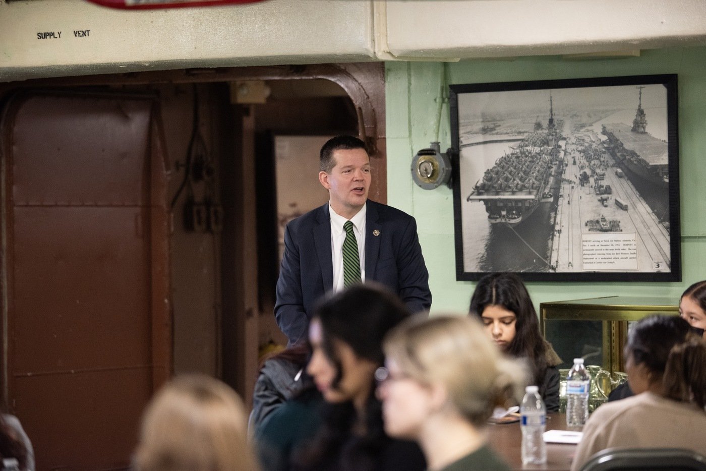 FBI San Francisco Assistant Special Agent in Charge Jonathan Blair presents to students in the wardroom of the USS Hornet during the field office's Summer 2023 Teen Academy in Alameda, California.