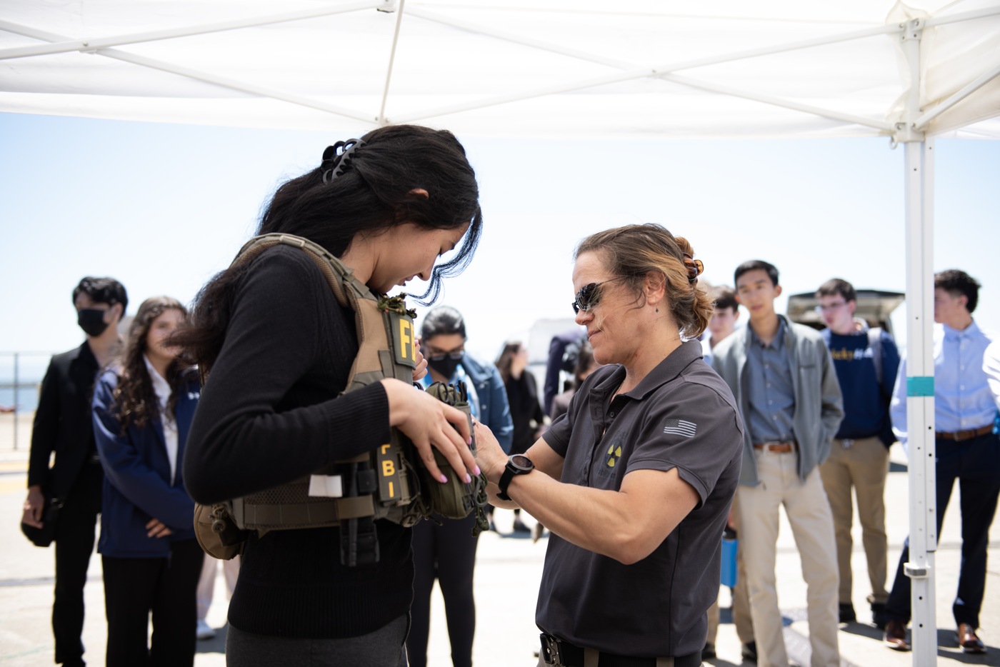 A special agent bomb technician (or SABT) helps a Teen Academy student with body armor during FBI San Francisco's Summer 2023 Teen Academy held in Alameda, California.