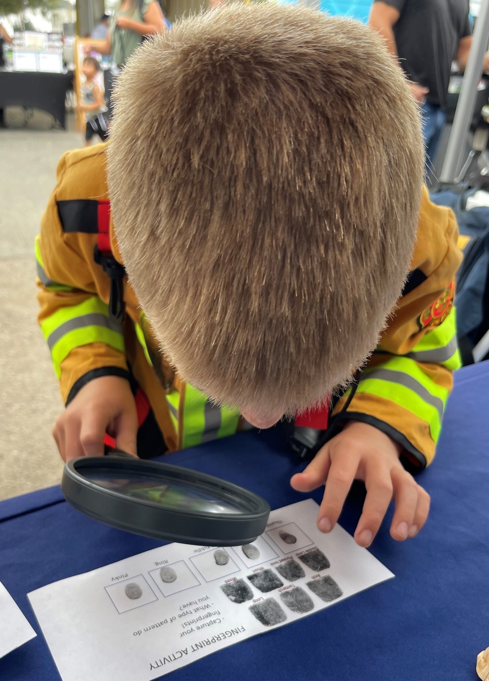 Child at the San Diego Family Safety Day event studies fingerprints.