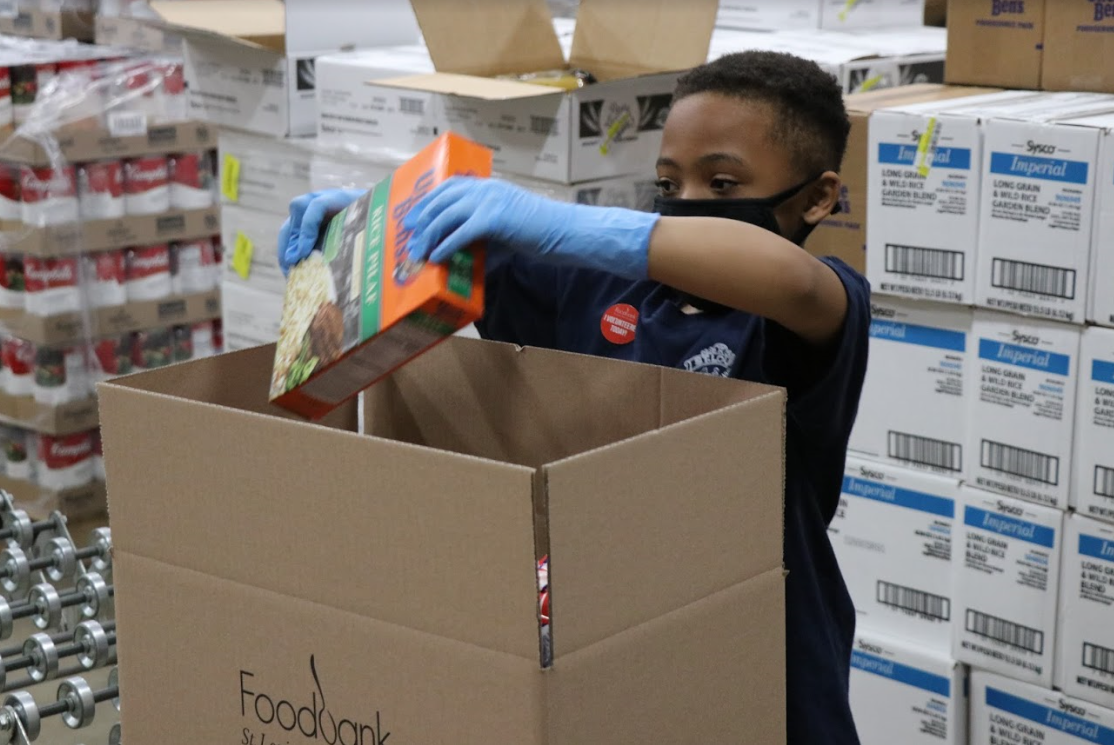 Officer Tamarris Bohannon's son helps pack food boxes at the St. Louis Area Foodbank.