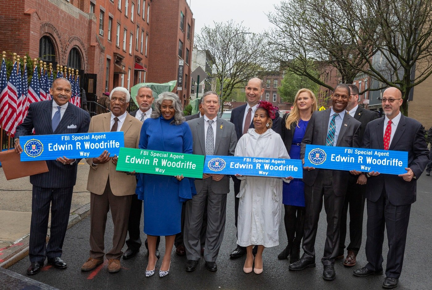 At an April 26, 2019 street renaming ceremony in New York, Woodriffe family members and FBI officials hold street signs bearing the name of Special Agent Edwin R. Woodriffe, who was the first African-American FBI agent killed in the line of duty.