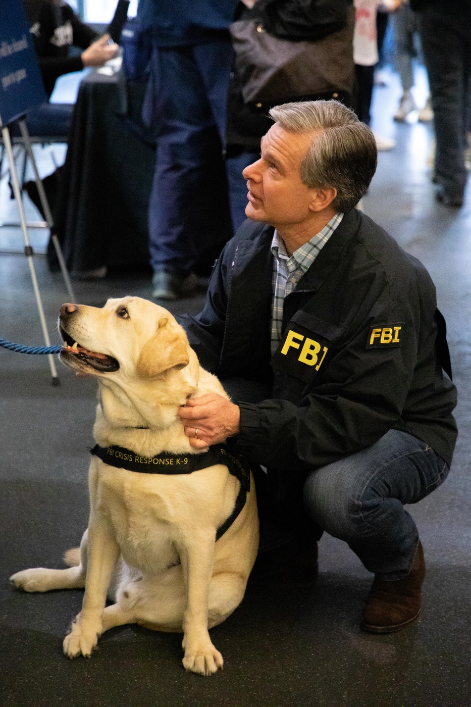 Director Wray pets Wally the FBI victim assistance dog before the FBI-U.S. Secret Service hockey game on April 30, 2022.