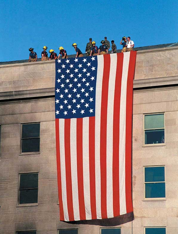 Rescue workers draping American flag at Pentagon after 9/11 attack